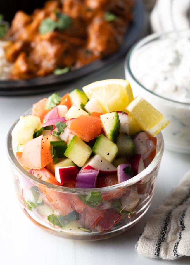 Chopped kachumber India salad in a glass bowl.