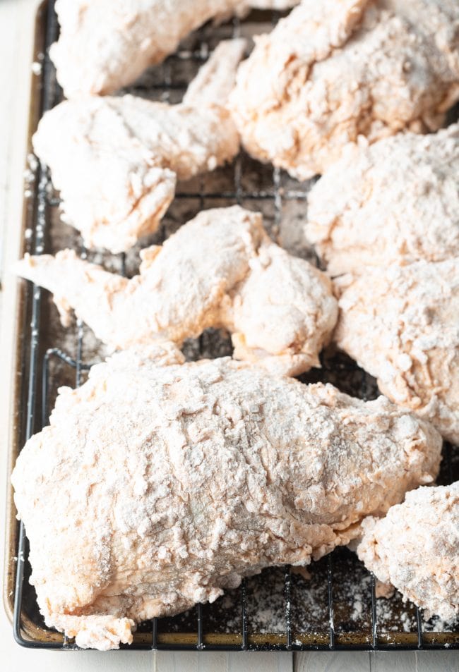 Breaded thighs and breasts on a rack before frying.