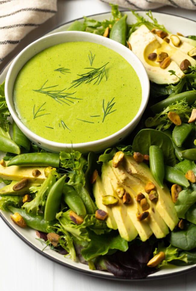 Bowl of salad with smaller bowl of dressing.