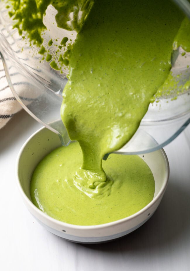 Pouring the homemade dressing from a blender jar into a small bowl.