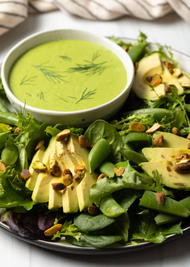 Plate of salad with bowl of dressing to the side.