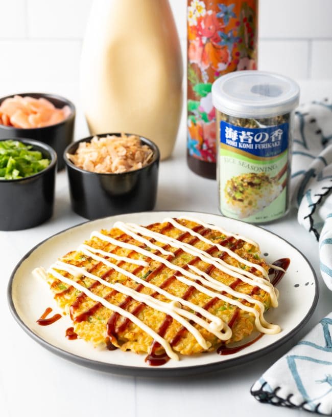 adding homemade Okonomiyaki sauce and kewpie mayo onto the cabbage pancake. 