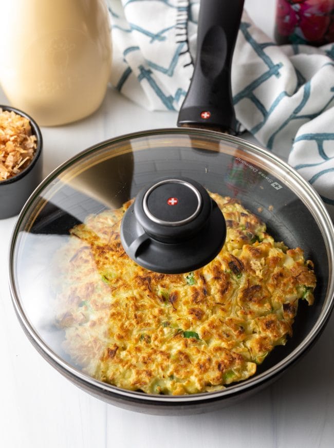 golden okonomiyaki in a skillet with lid