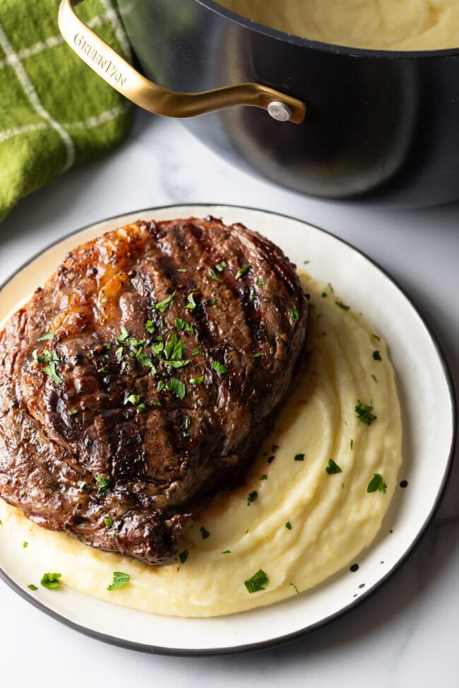 Grilled steak on top of a bed of whipped potatoes.