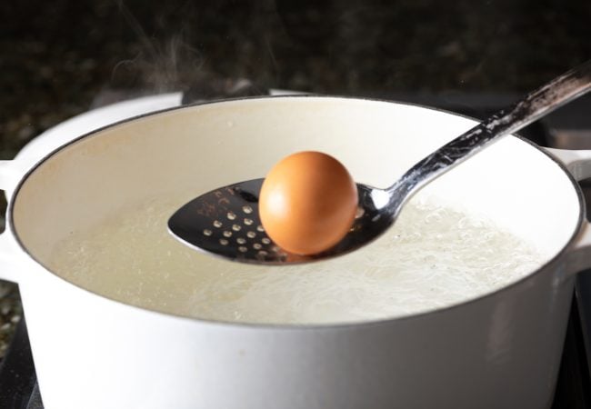 lowering egg into boiling water