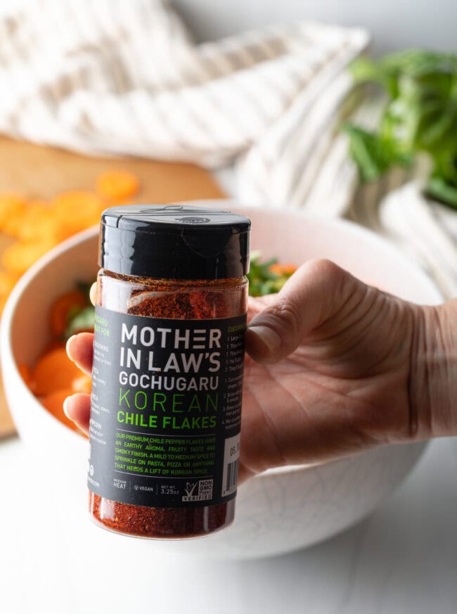 Hand with jar of Mother in Laws kimchi blend to camera.