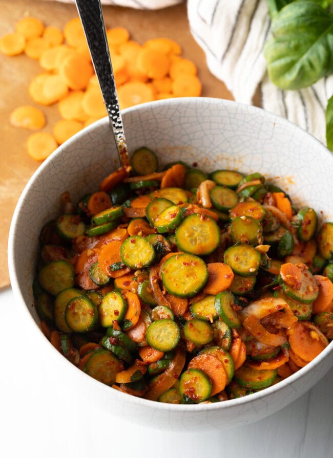 Salad with Korean marinated veggies tossed together in a white bowl.