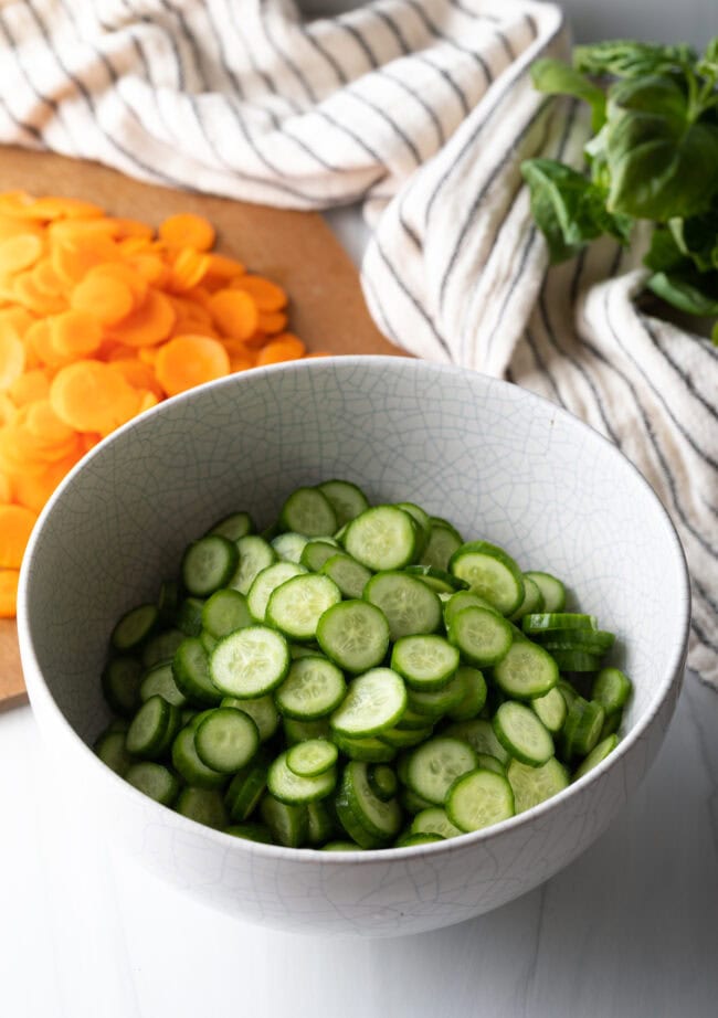 Thinly sliced cucumber rounds in a white bowl.