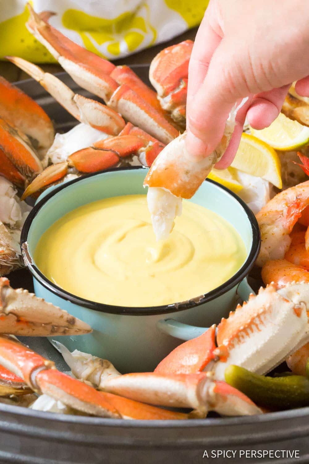 Mustard seafood dipping sauce in a small bowl on a serving platter with crab. 