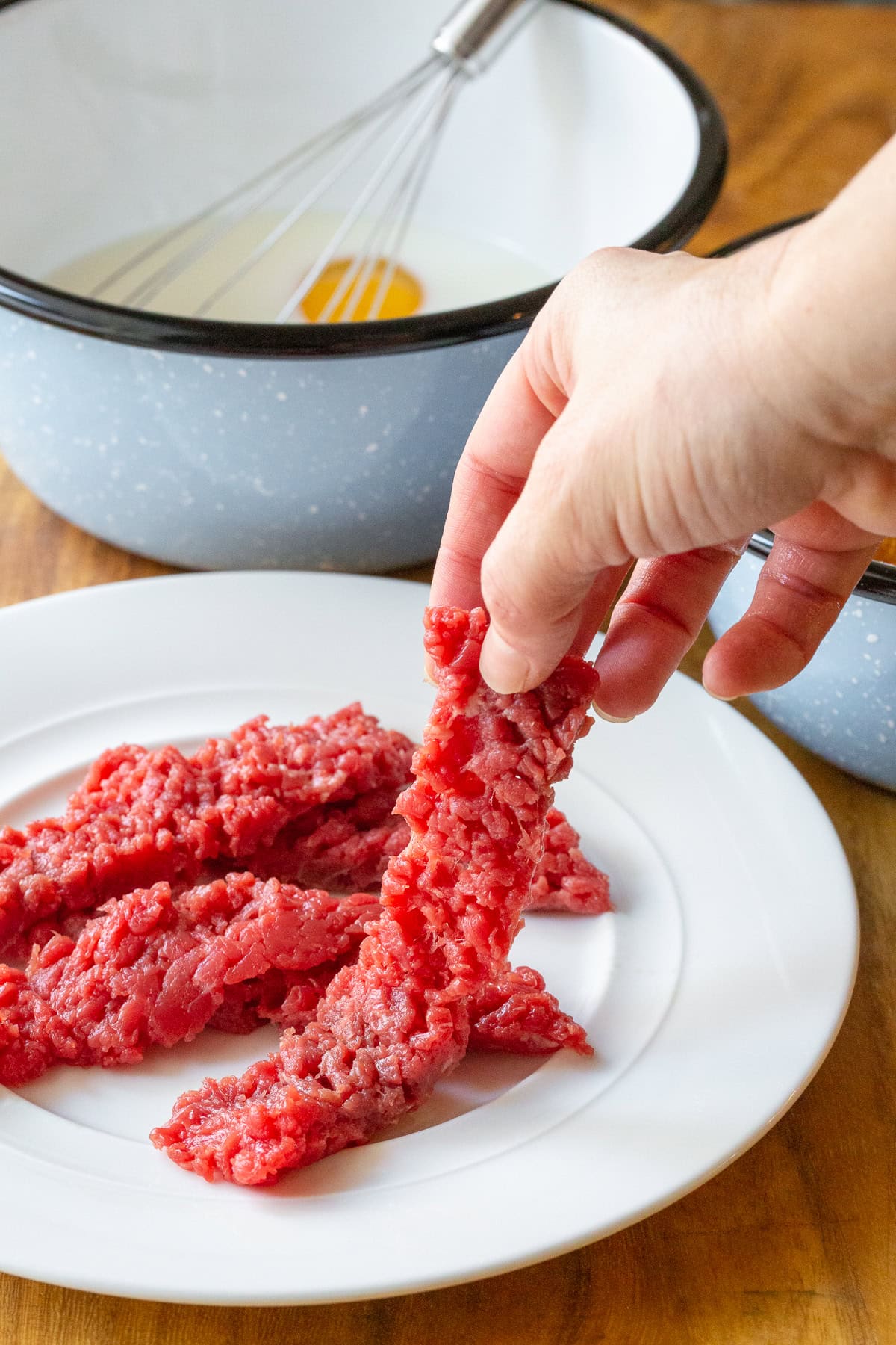 Steak Fingers Recipe - Hand holding raw beef before breading it and frying it. 