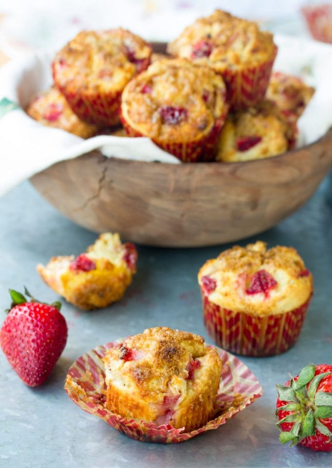 Rhubarb muffin with the wrapper opened to show the full muffin with more muffins in the background. 