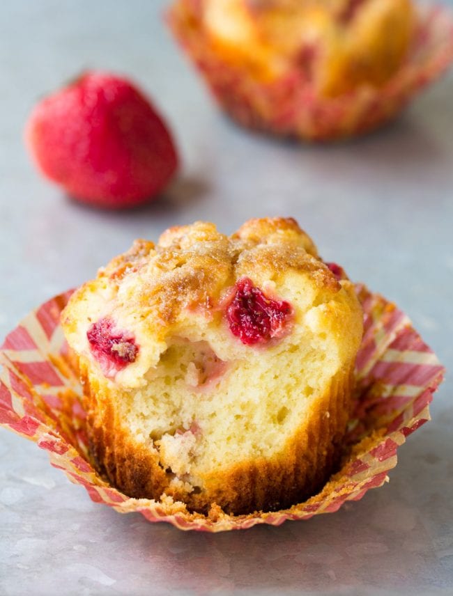 Strawberry rhubarb muffin with a bite missing to show the inside of the muffin. 