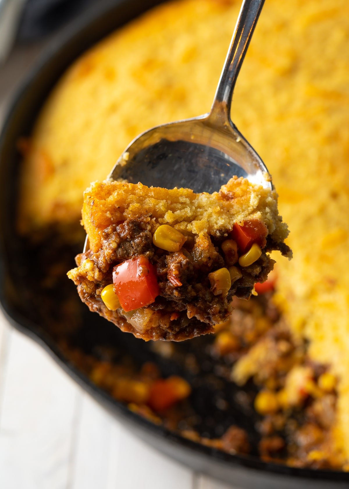 Scoop of Easy Tamale Pie on a spoon with the rest of the pie in the background. 