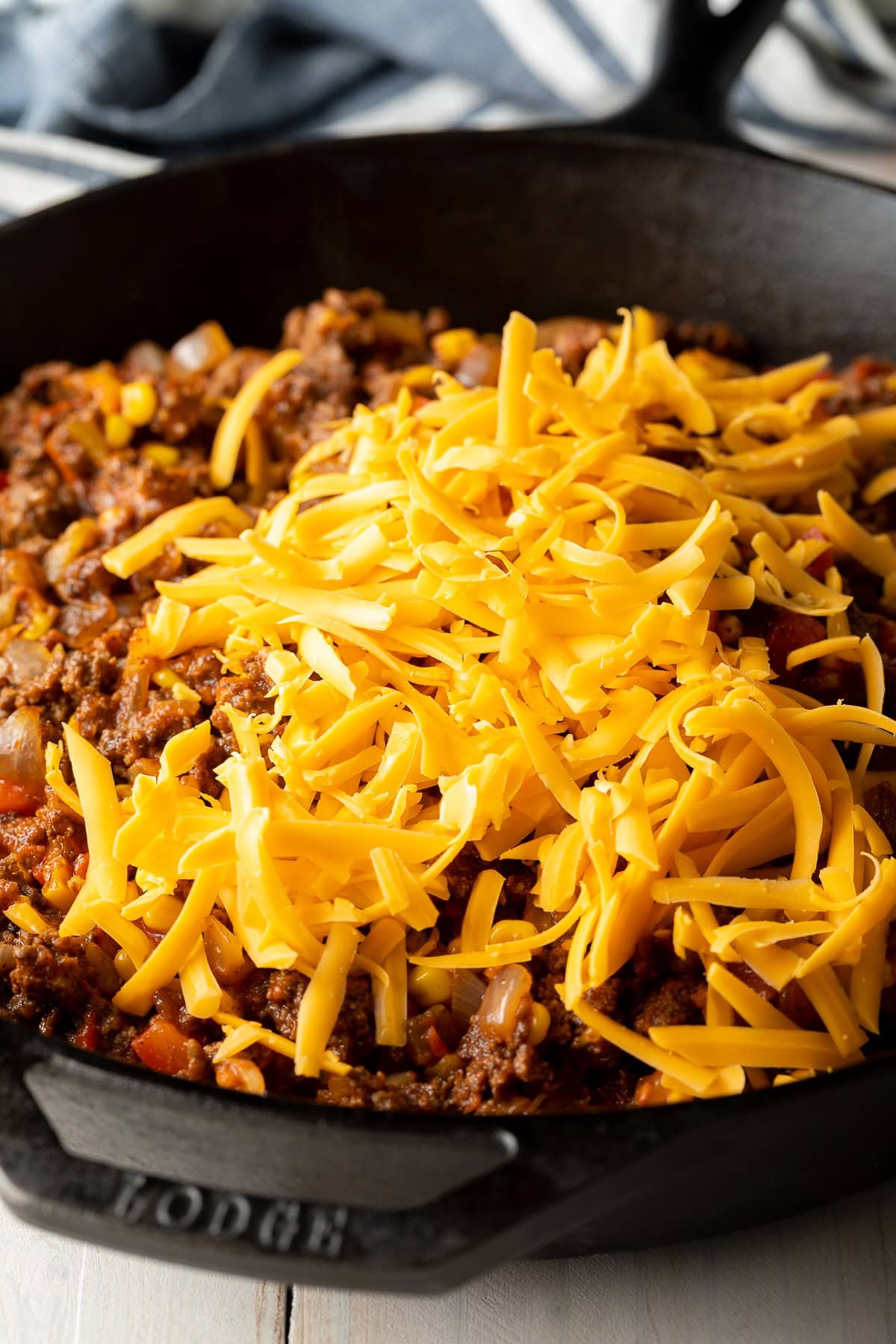 Shredded cheese on top of the meat mixture in a cast iron skillet. 