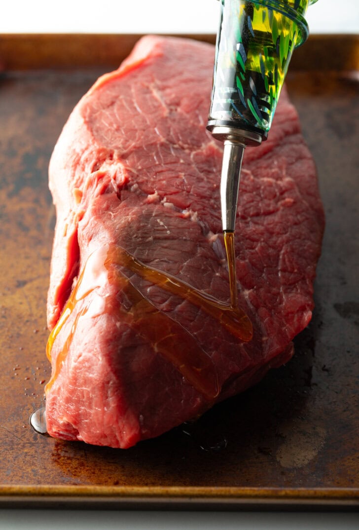 Coating a large piece of raw been with olive oil.