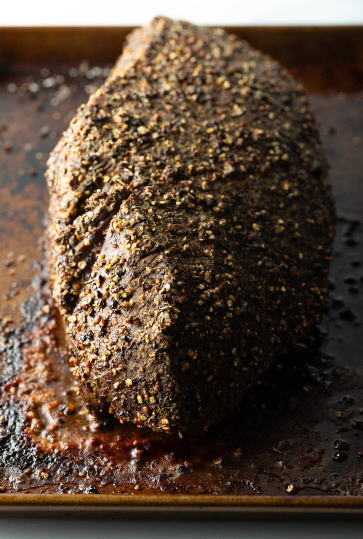 Top down view cooked beef round roast on a metal baking pan.